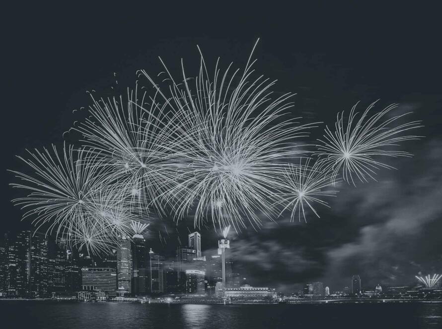 Aerial view of fireworks above a city waterfront at night